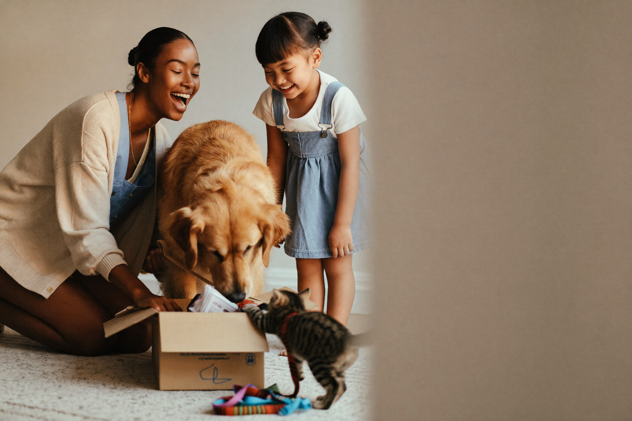 Mum and daughter unboxing a WaggleBox delivery with their golden retriever and kitten